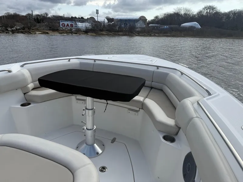 Slide: The Image of 2018 Boston Whaler 330 Outrage boat with cushioned seating and table on calm water. - 16