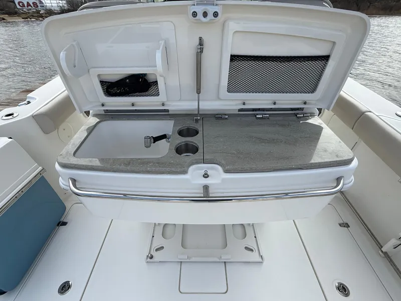 Slide: The Image of 2018 Boston Whaler 330 Outrage boat with open storage compartment and sink on deck. - 8
