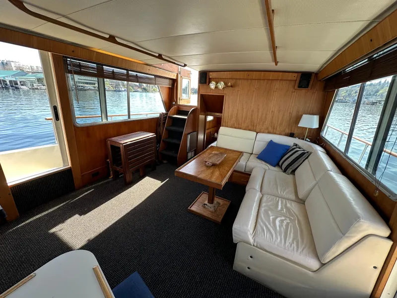 Slide: The Image of 1982 Tollycraft Tri Cabin interior with white leather seating, wooden table, and waterfront view. - 29