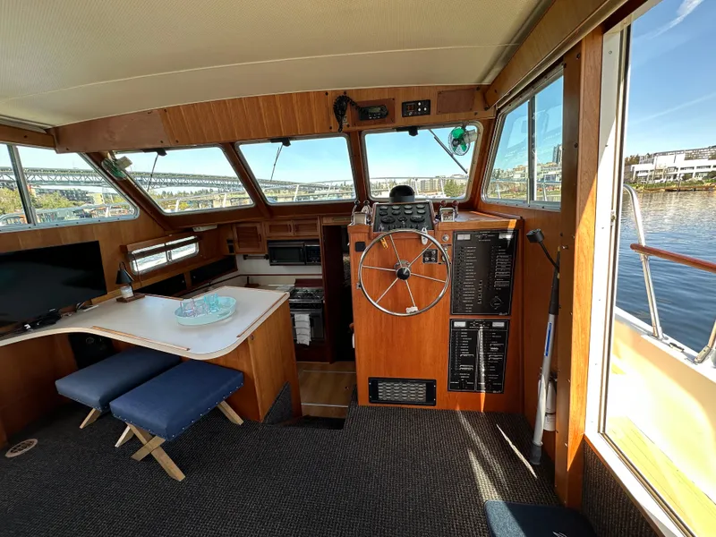 Slide: The Image of 1982 Tollycraft Tri Cabin interior with helm, dining area, and waterfront view. - 31