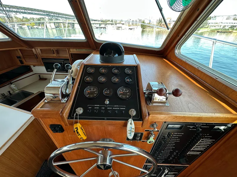 Slide: The Image of 1982 Tollycraft Tri Cabin helm with gauges, steering wheel, and waterfront view. - 32