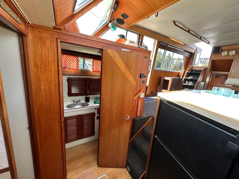 Slide: The Image of 1982 Tollycraft Tri Cabin interior with wood paneling, kitchenette, and natural light. - 42