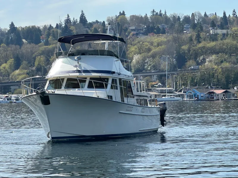 Slide: The Image of 1982 Tollycraft Tri Cabin boat on a serene lake with forested hills in the background. - 5