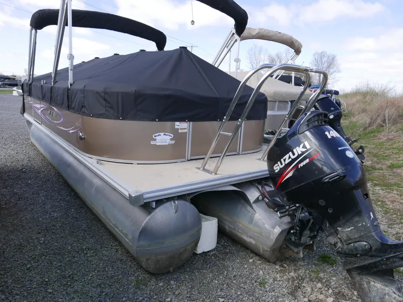 Slide: The Image of 2012 Sylvan Mirage 8522 LZ pontoon boat with Suzuki 140 outboard motor, covered and parked. - 4