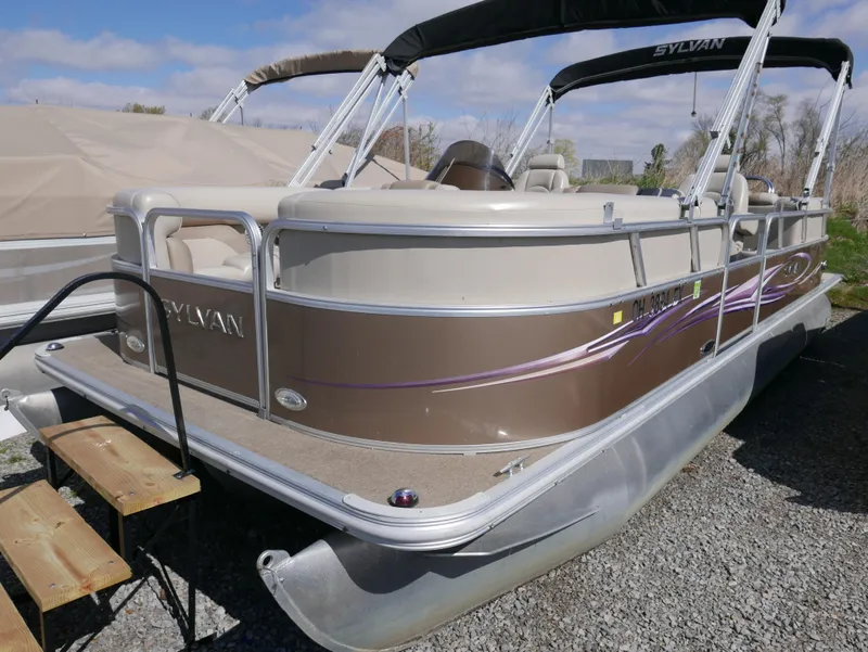 Slide: The Image of 2012 Sylvan Mirage 8522 LZ pontoon boat with brown exterior, docked on gravel. - 5