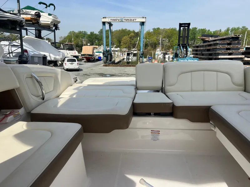 Slide: The Image of 2014 Chaparral 257 SSX boat interior with white and brown seating at a marina. - 2