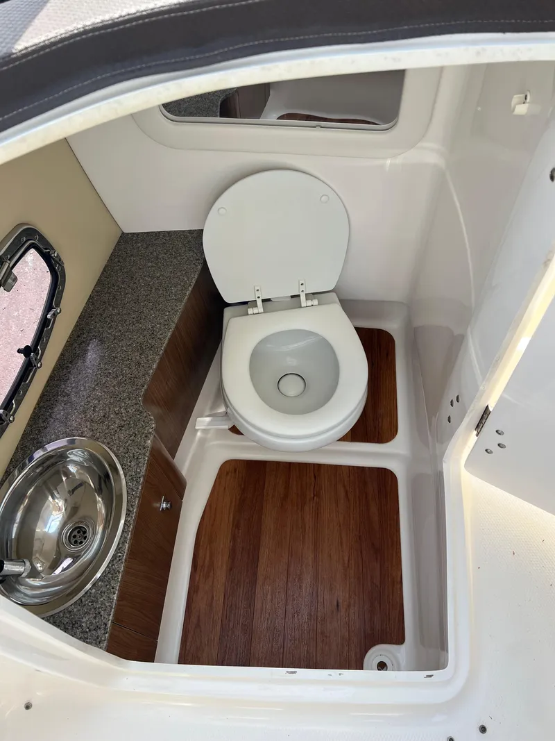 Slide: The Image of 2014 Chaparral 257 SSX boat bathroom with toilet, sink, and wood flooring. - 7