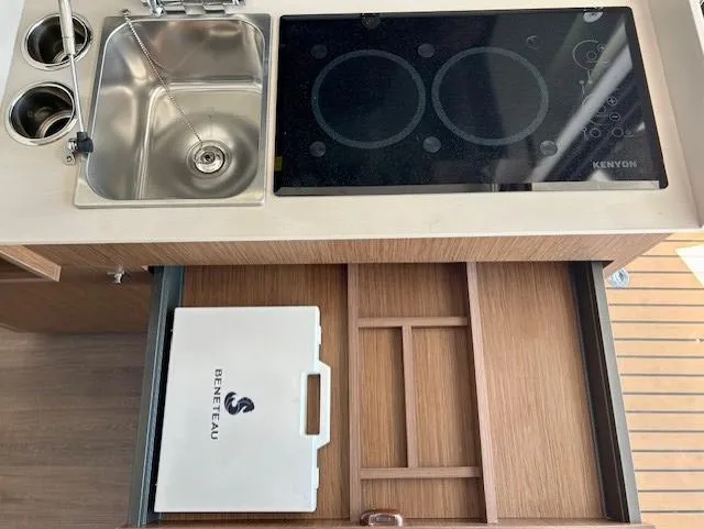 Slide: The Image of 2024 Beneteau Antares 9 kitchen with sink, stove, and organized storage drawer. - 14