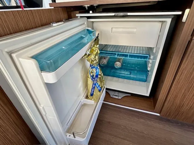 Slide: The Image of Open refrigerator inside 2024 Beneteau Antares 9 boat, showing drinks and a bottle. - 16