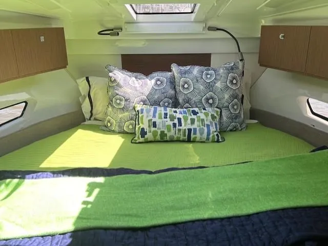 Slide: The Image of 2024 Beneteau Antares 9 cabin interior with green bedding and decorative pillows. - 24