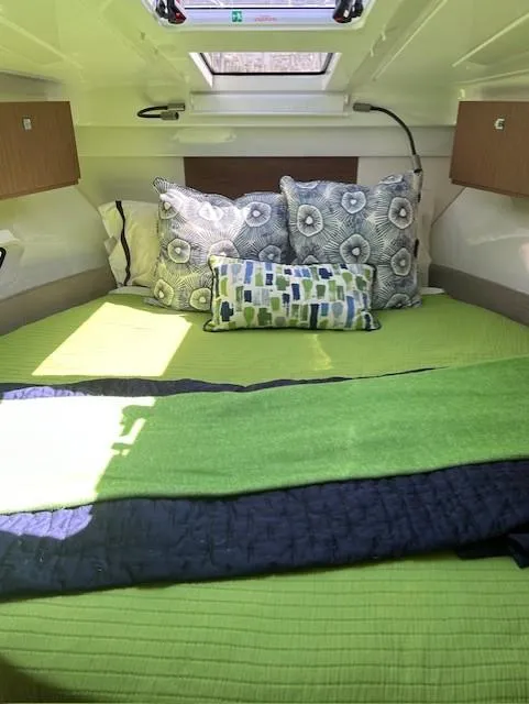 Slide: The Image of 2024 Beneteau Antares 9 cabin interior with green bedding and decorative pillows. - 25