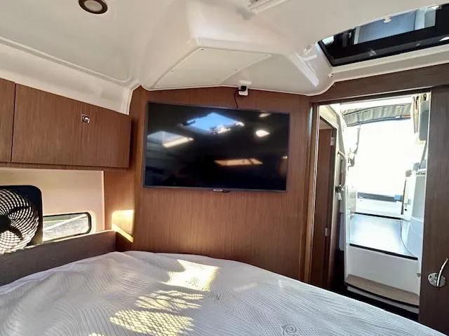 Slide: The Image of 2024 Beneteau Antares 9 cabin interior with TV, wood paneling, and bed. - 26