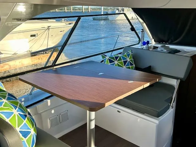 Slide: The Image of Interior of 2024 Beneteau Antares 9 with dining table and colorful cushions. - 9