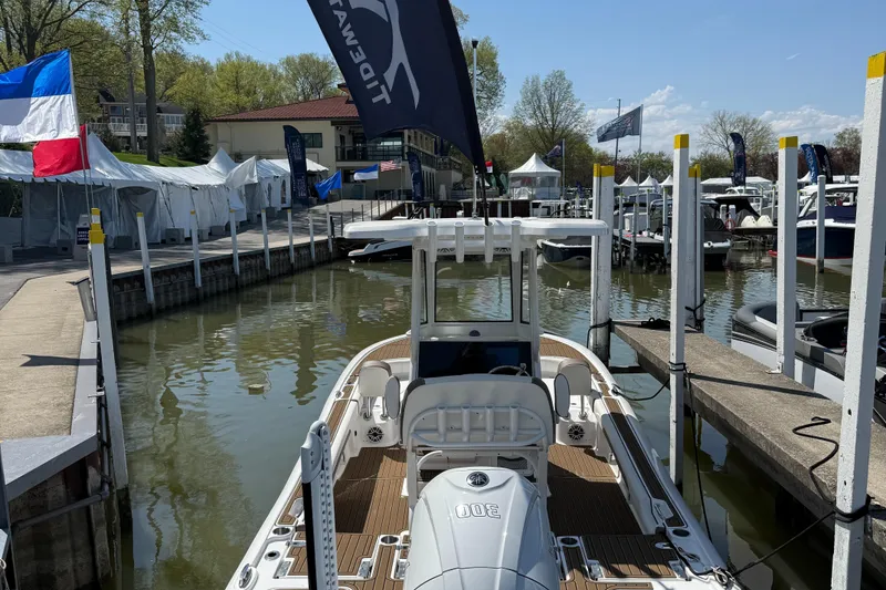 Slide: The Image of 2025 Tidewater 2500 Carolina Bay boat docked at marina with flags and tents. - 10