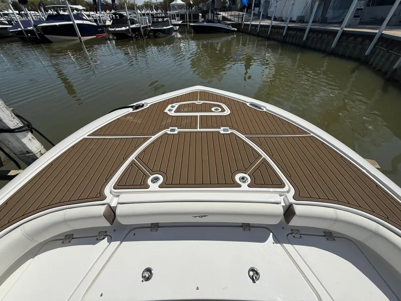 Slide: The Image of 2025 Tidewater 2500 Carolina Bay boat with teak deck, docked in a marina. - 9