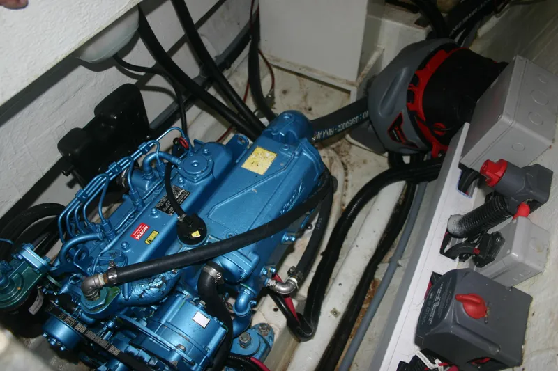 Slide: The Image of Engine compartment of a 2009 Prout 45S, featuring a blue marine engine and control switches. - 46