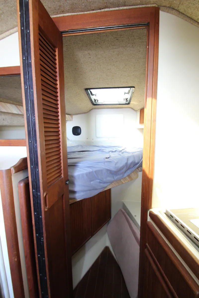 Slide: The Image of 1990 Boston Whaler 31 Sportfisherman cabin interior with bed and wooden accents. - 20