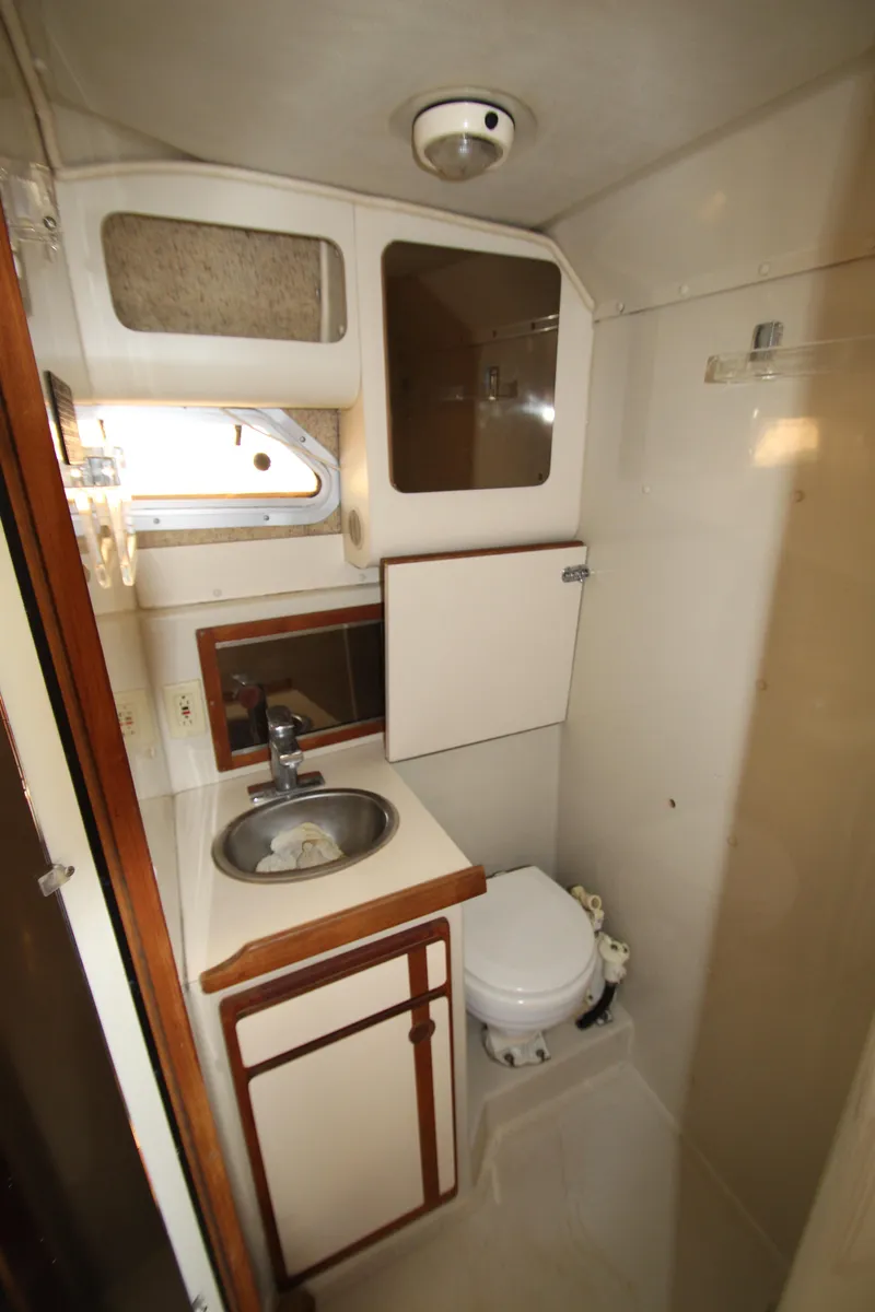 Slide: The Image of 1990 Boston Whaler 31 Sportfisherman bathroom with sink, toilet, and storage cabinets. - 24