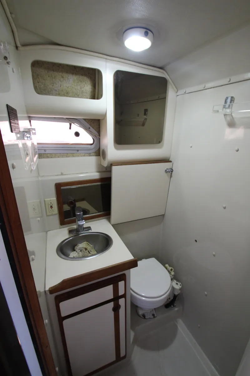 Slide: The Image of 1990 Boston Whaler 31 Sportfisherman bathroom with sink, toilet, and storage cabinets. - 26