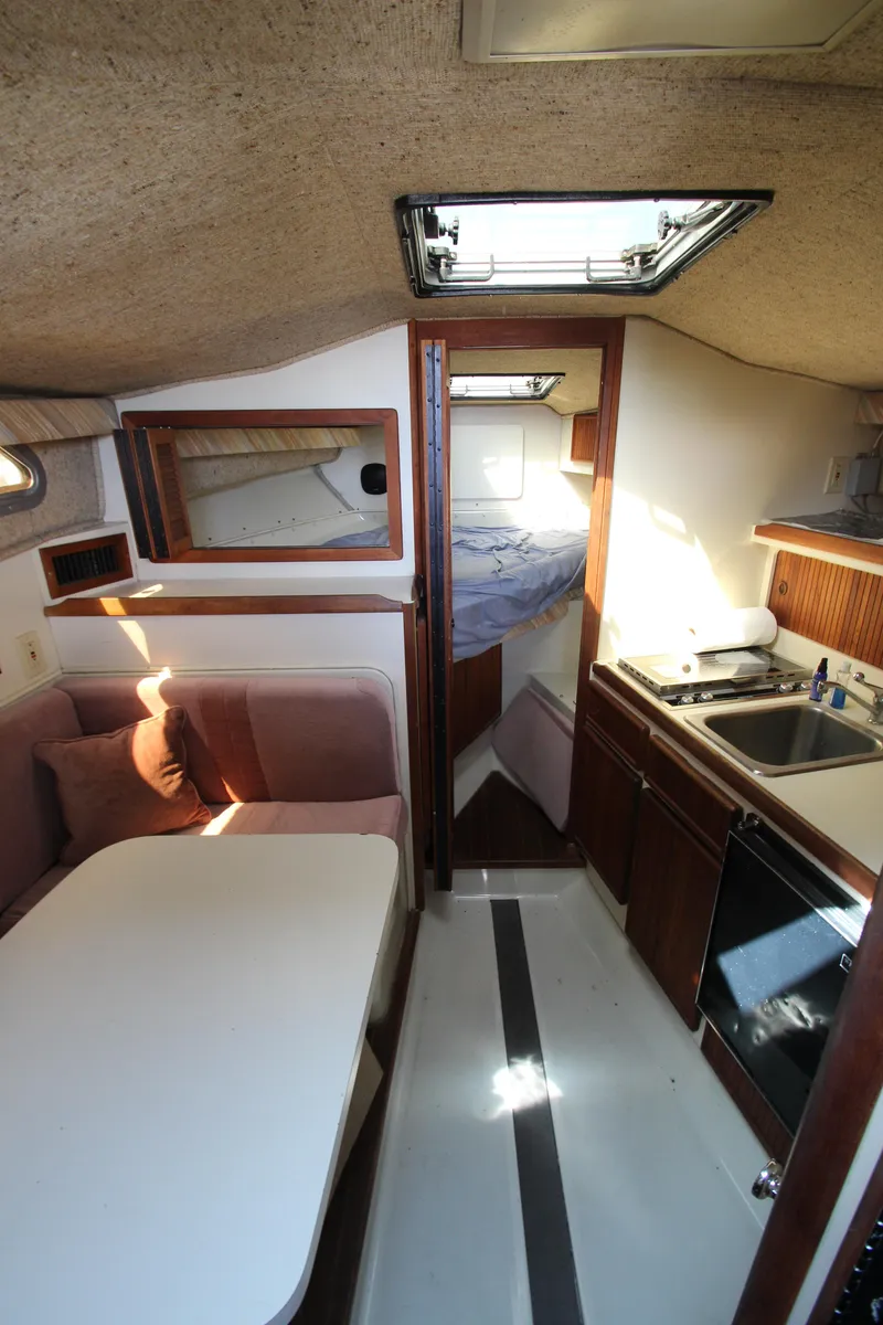 Slide: The Image of Interior of a 1990 Boston Whaler 31 Sportfisherman, featuring a cozy dining area and compact kitchen. - 30