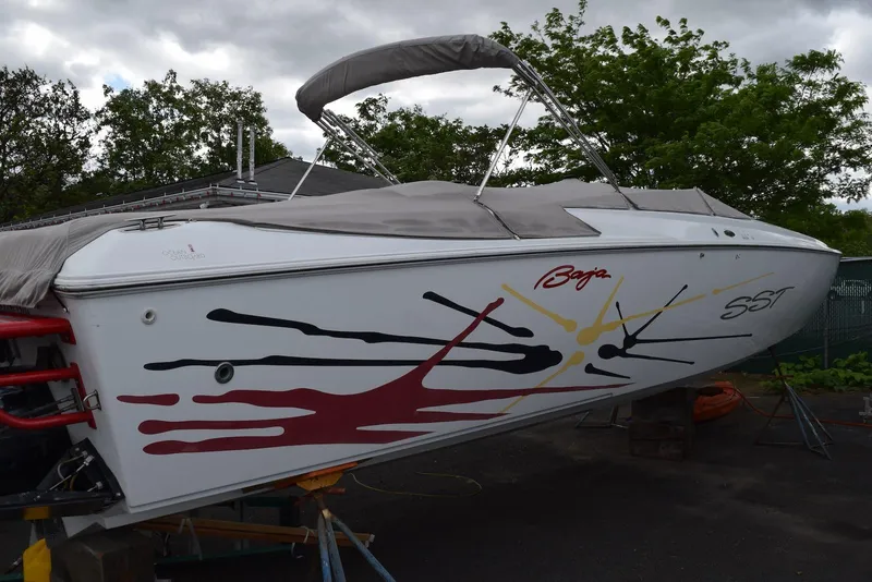 Slide: The Image of 2000 Baja 40 Outlaw speedboat with colorful graphics, parked outdoors. - 14