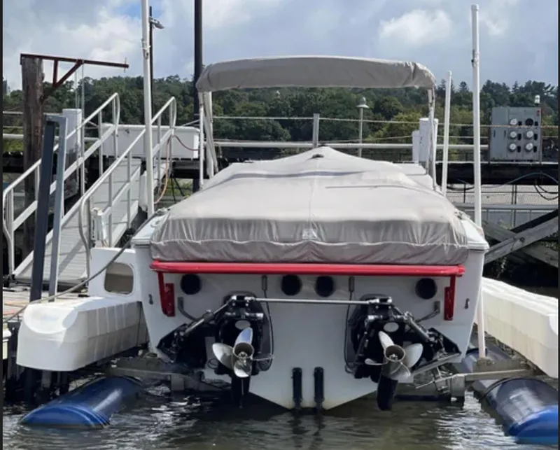 Slide: The Image of 2000 Baja 40 Outlaw boat docked, rear view with covered deck and dual propellers. - 16