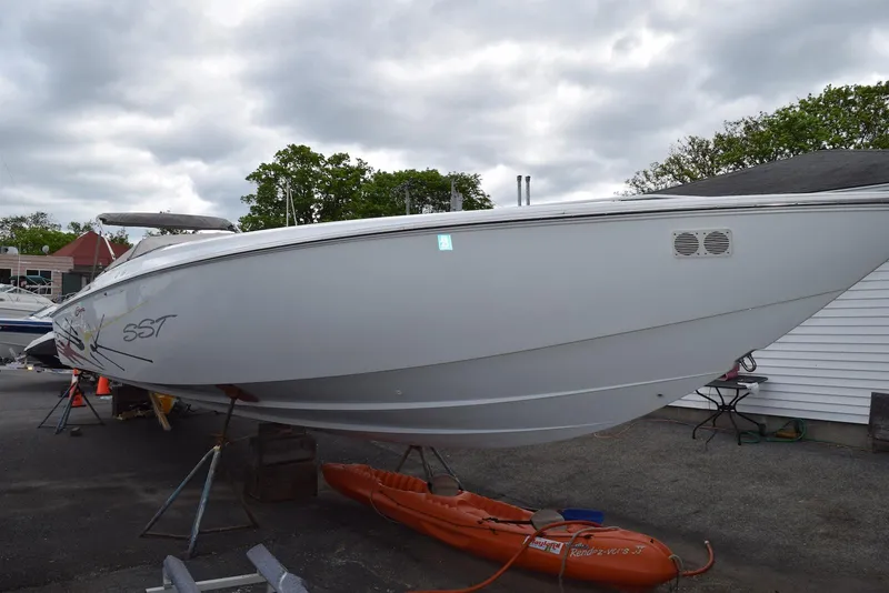 Slide: The Image of 2000 Baja 40 Outlaw boat on dry dock, overcast sky, orange kayak nearby. - 5