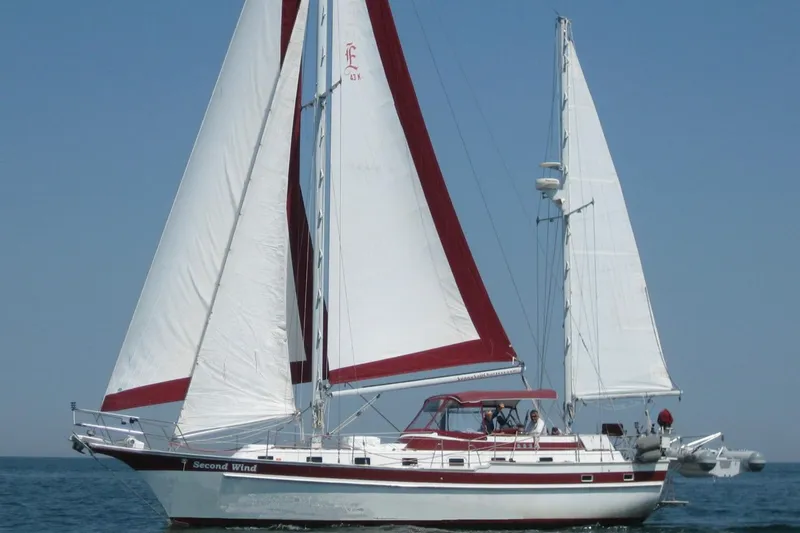 The Image of 1981 Endeavour 43 sailboat with red and white sails on open water. - 0