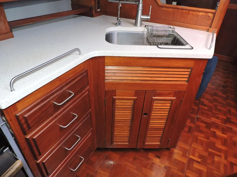 Slide: The Image of 1981 Endeavour 43 yacht kitchen with wooden cabinets, stainless steel sink, and white countertop. - 10