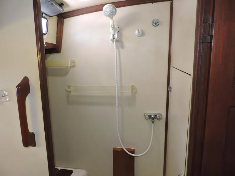 Slide: The Image of 1981 Endeavour 43 yacht bathroom with showerhead, wooden accents, and storage shelves. - 18