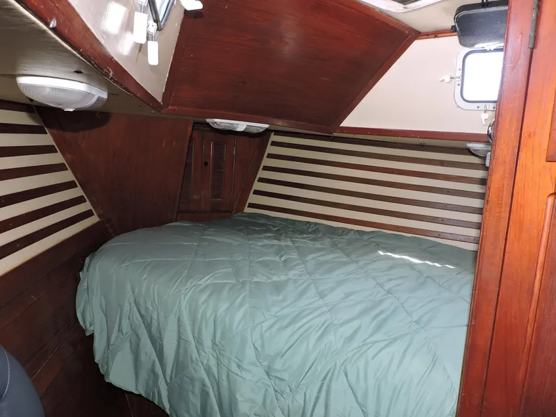 Slide: The Image of Cozy cabin interior of 1981 Endeavour 43 sailboat with wood paneling and green bedding. - 19