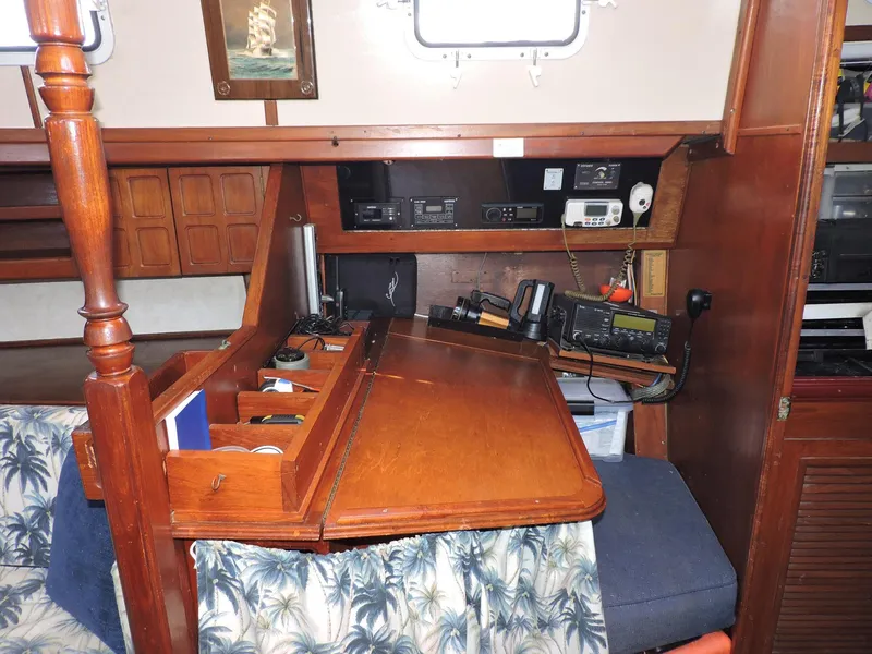 Slide: The Image of Navigation station inside 1981 Endeavour 43 sailboat with wooden desk and communication equipment. - 22