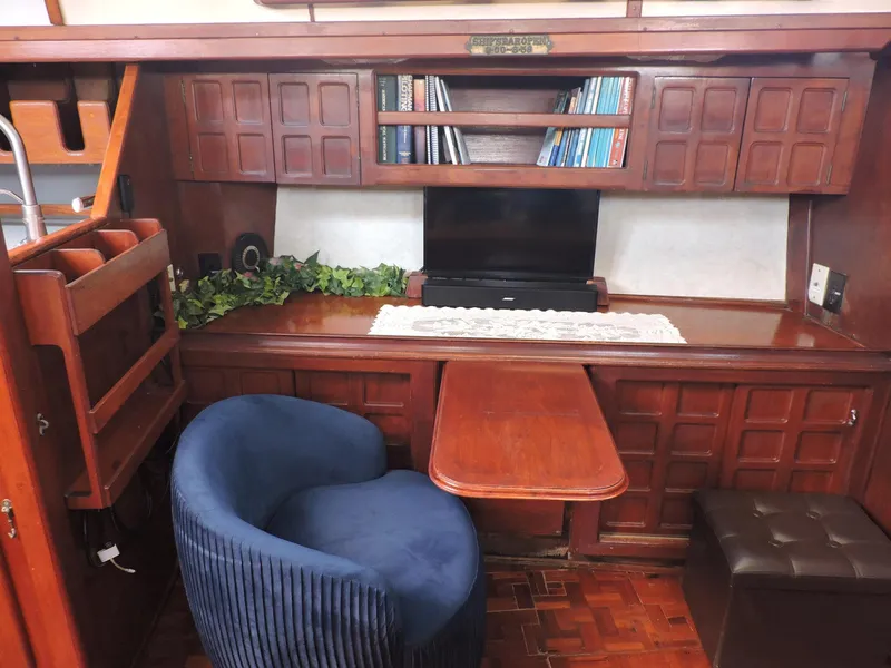 Slide: The Image of Cozy 1981 Endeavour 43 yacht interior with wooden cabinetry, blue chair, and bookshelves. - 8