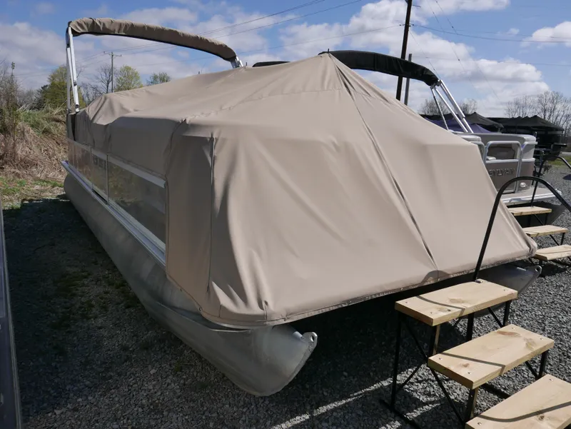 Slide: The Image of 2004 Sylvan Mirage 8522 pontoon boat covered with beige tarp, parked on gravel. - 2