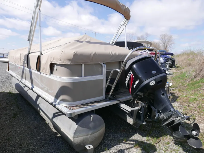Slide: The Image of 2004 Sylvan Mirage 8522 pontoon boat with covered deck and outboard motor, parked on gravel. - 4