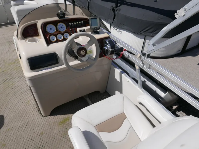 Slide: The Image of 2004 Sylvan Mirage 8522 boat dashboard with steering wheel and gauges. - 8