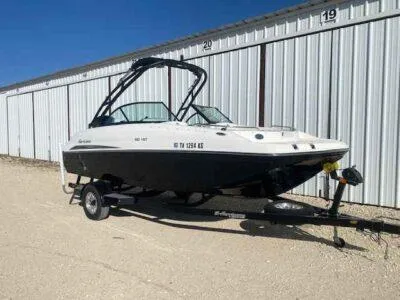 Slide: The Image of 2023 Hurricane SunDeck 187 OB boat on trailer, parked outdoors near storage units. - 1