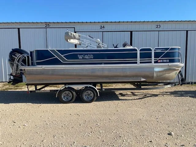 Slide: The Image of 2024 SunCatcher Fusion 322FC pontoon boat on trailer, parked outdoors. - 0