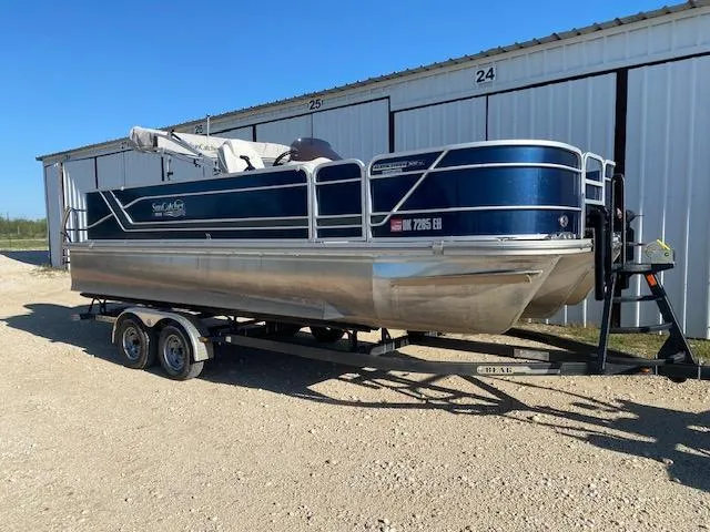 Slide: The Image of 2024 SunCatcher Fusion 322FC pontoon boat on trailer, parked outdoors. - 1
