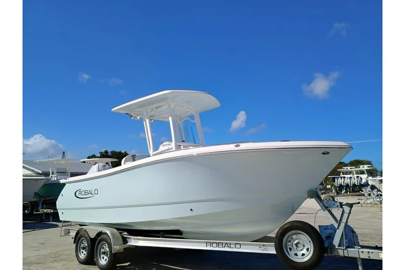 The Image of 2025 Robalo R230 Center Console boat on trailer under clear blue sky. - 1