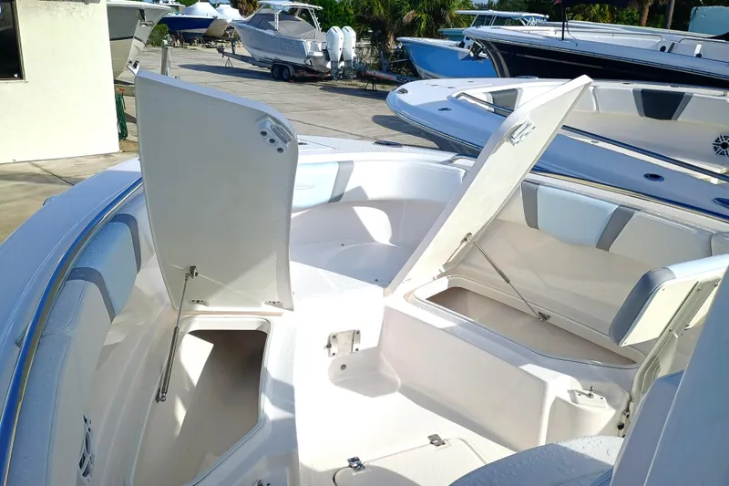 Slide: The Image of 2025 Robalo R230 Center Console boat with open storage compartments, docked outdoors. - 11