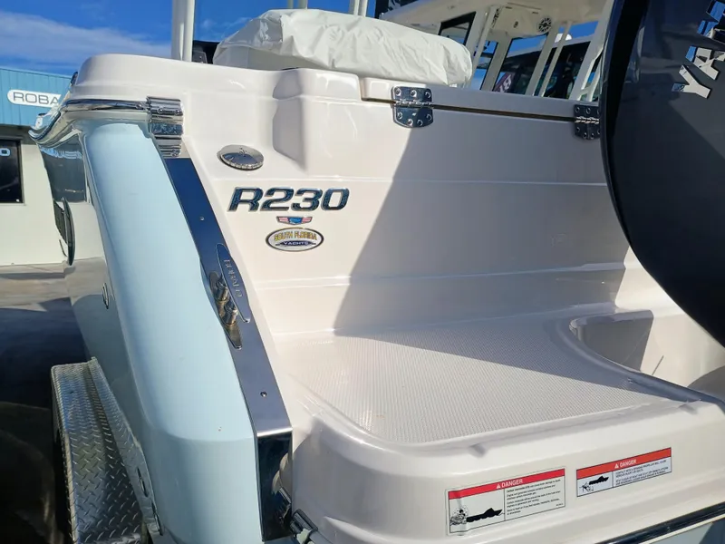 Slide: The Image of 2025 Robalo R230 Center Console boat, rear view with branding and safety labels. - 22