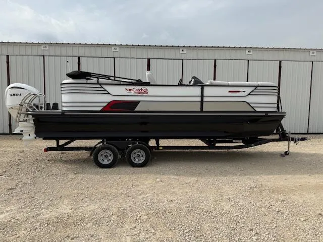 The Image of 2025 SunCatcher Elite 324 RC pontoon boat on trailer, parked outdoors. - 0
