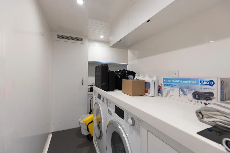 Slide: The Image of Laundry room inside 2022 Riviera 645 SUV yacht with washer, dryer, and storage. - 30