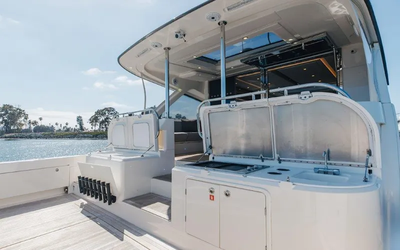 Slide: The Image of 2022 Riviera 645 SUV yacht with outdoor kitchen and seating area, docked by the water. - 6