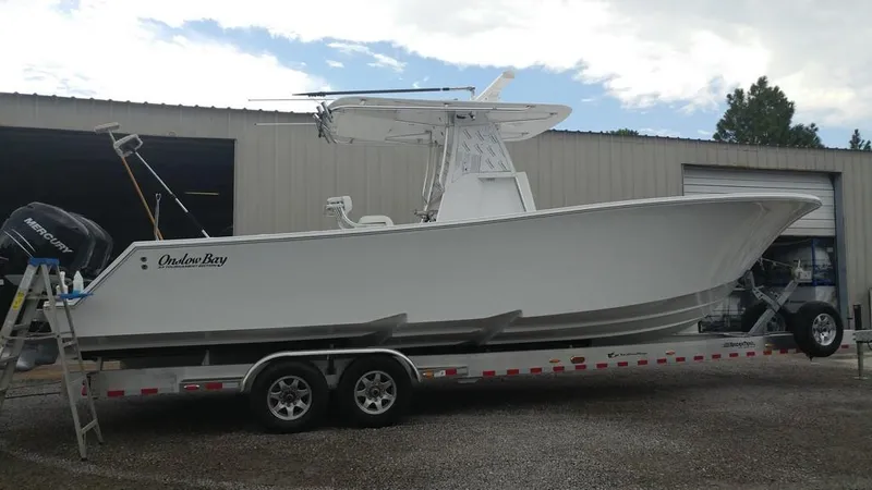 Slide: The Image of 2019 Onslow Bay 33 Tournament boat on trailer, parked outside a warehouse. - 36