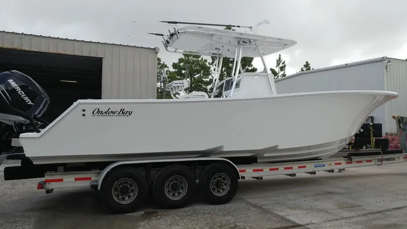 Slide: The Image of 2019 Onslow Bay 33 Tournament boat on a trailer, parked outside a warehouse. - 44