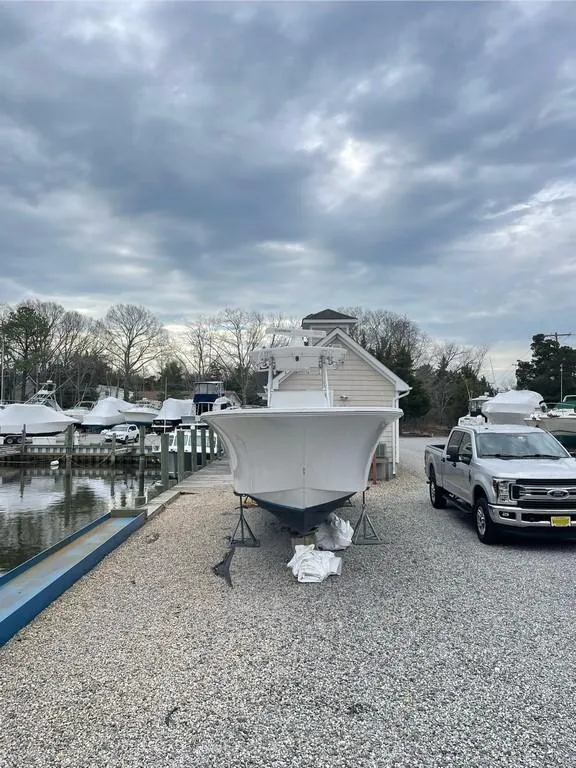 Slide: The Image of 2019 Onslow Bay 33 Tournament boat on trailer, parked near marina under cloudy sky. - 7
