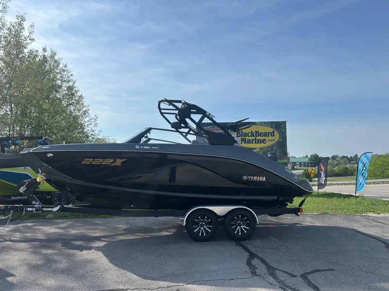 Slide: The Image of 2025 Yamaha Boats 222XD in black, parked outdoors on a trailer. - 2