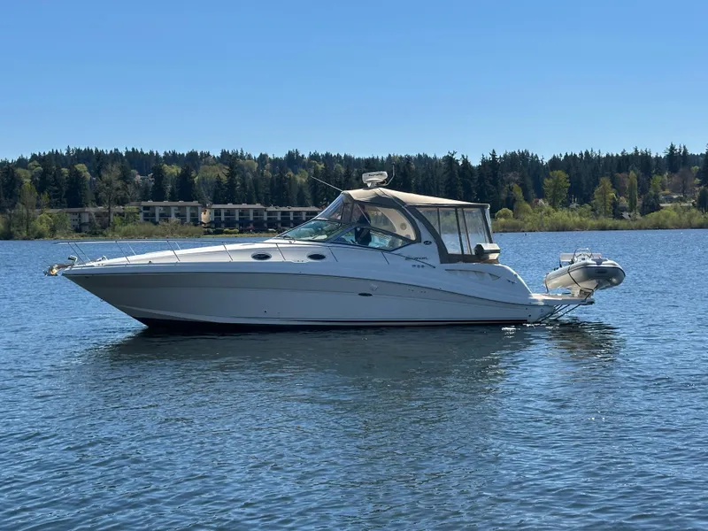 Slide: The Image of 2004 Sea Ray 340 Sundancer boat on a calm lake with forested shoreline. - 0